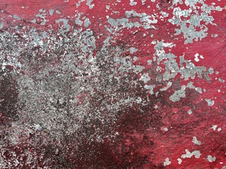 Close-up of weathered red wall with peeling paint and rough textured surface, creating an abstract rustic background.