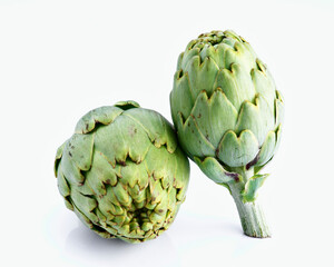 Two fresh artichokes resting on white reflective surface