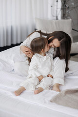 Mother and daughter share a bonding moment in cozy bedroom at morning light
