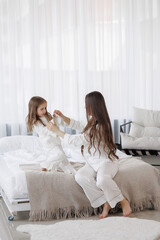 Mother and daughter enjoy playful bonding time at home in cozy white outfits