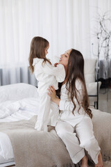 Parent and child share a joyful moment in a modern bedroom during morning hours