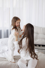 Mom and daughter enjoying quality time together in cozy white pajamas at home