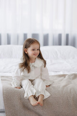 Young girl sitting on bed in cozy bedroom during morning