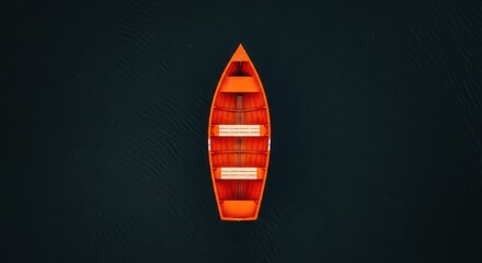 An empty orange rowboat floats serenely on dark, rippling water, viewed from directly above