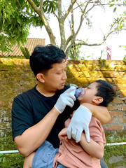 Father giving nebulizer therapy to his sick son outdoors
