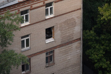 Close-up view of an old Soviet brick apartment building with a broken window, weathered facade and...