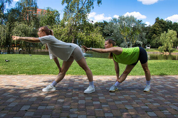 Two young women in sportswear doing stretching exercise in the park