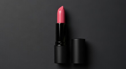 A sleek pink lipstick with its cap resting beside it, presented against a minimalist black background