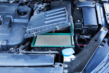 Old dirty air filter in the underhood space of the car. Car maintenance, close-up