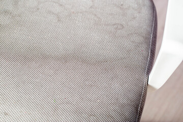 Dirty gray upholstery fabric with stains on computer chair before dry cleaning, close-up
