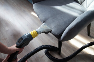 Services for washing and cleaning upholstered furniture with a vacuum cleaner. Cleaning dirty gray...
