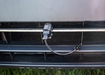 Black car outside air temperature sensor against the background of a car bumper grille. Measuring...