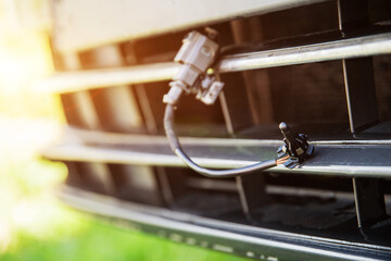 Black car outside air temperature gauge against car bumper grille at sunset. Car air measurement...