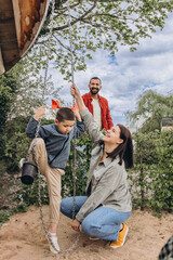 Multinational family with 6 year old boy playing together at playground. Parents involved in active...