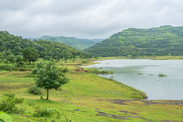A picturesque view of the Dimbhe Dam backwater, Serene landscape with lush green hills and tranquil...