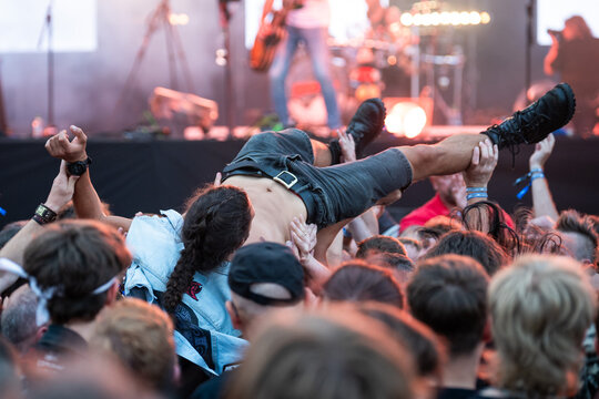 Crowd of people in front of the stage during the concert and crowd surfing man.