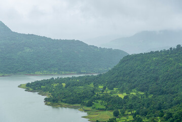 A picturesque view of the Dimbhe Dam backwater, Serene landscape with lush green hills and tranquil...