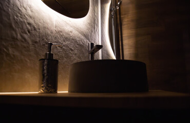 Stone sink in the dark in the bathroom against the background of a mirror with diode backlighting...