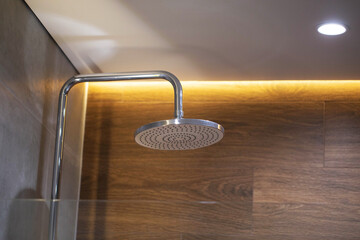 Modern chrome shower in the bathroom against the background of a suspended ceiling and a yellow LED...