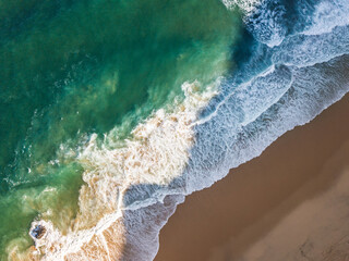 Aerial View of Ocean Waves Hitting Sandy Shore. Aerial drone view. natural background