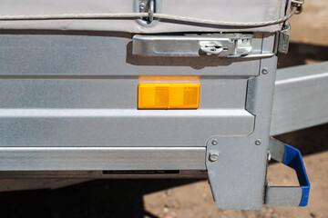 orange reflector on the side of a galvanized trailer body, close-up