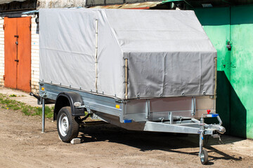 Gray single axle tarpaulin trailer for transporting cargo for a passenger car, copy space for text