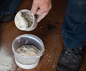 Dolomite flour in a mug against the background of a bucket, fertilizing the soil at the dacha,...