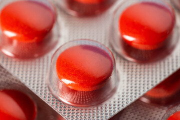 Red tablets in a blister, macro. Concept of sedative tablets and sleeping pills, macro