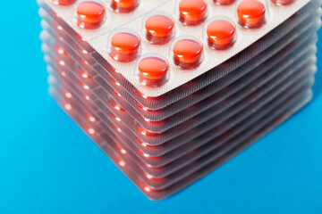Stack of red pills on blue background for hangover, close-up