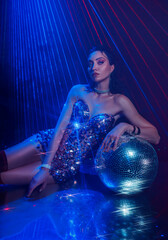 fashion model woman posing in dark black room night club full smoke rays laser party with disco ball, neon blue color light. Sexy face lady, fun girl glow shiny dress wet hair hairstyle glamou makeup