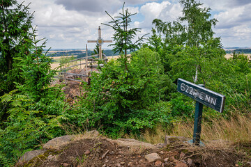 Blick auf das Gipfelkreuz auf dem Burgberg in Lichtenberg; ein Schild zeigt die Höhe über NN an