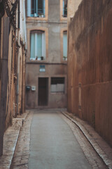 Fototapeta premium Narrow alleyway in a historic urban area with weathered buildings and a quiet atmosphere during daylight hours