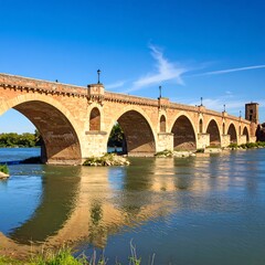 Fototapeta premium Ancient stone bridge spanning a river under a clear sky