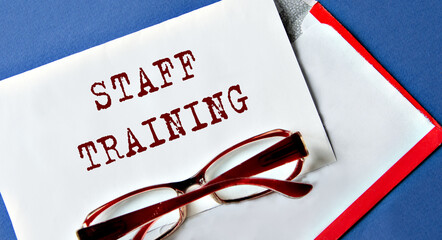 STAFF TRAINING - words on a white sheet with an envelope and glasses on the background