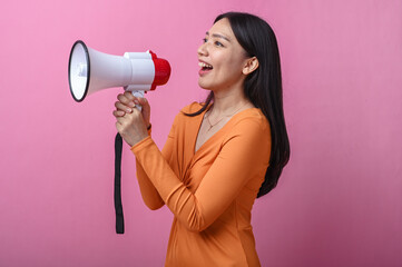 Asian woman with long black hair wearing an orange dress holding a white and red megaphone,...