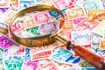 Collection of stamps and magnifying glass.A collection of world stamps in a pile.Postage stamps...