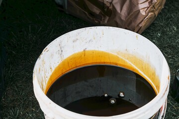 Dark motor oil inside used white container