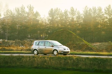 Compact car driving on sunny rural road