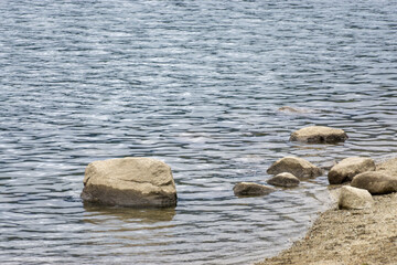 A large rock sits in the middle of a body of water