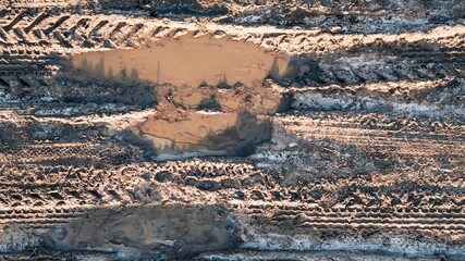 Muddy puddles and tire tracks creating rough terrain on dirt road