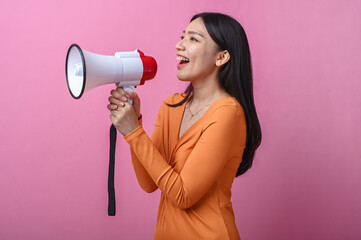 Asian woman with long black hair wearing an orange dress holding a white and red megaphone,...