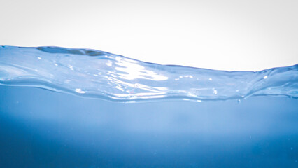 This image captures a dynamic splash of blue water with bubbles and gentle waves against a clean...