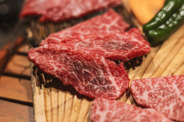 raw beef steak, A5 Wagyu on wooden plate, Japanese beef for yakiniku, high quality meat from Japan, BBQ meal in All-you-can-eat restaurant