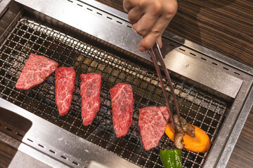 cooking raw beef meat on grill with fire and heat, metal wire grill equipment, high quality wagyu with beautiful fat