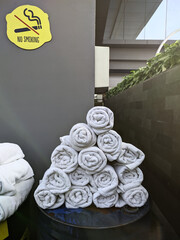 Neatly rolled white towels ready for guests at a hotel swimming pool area, under a prominent 