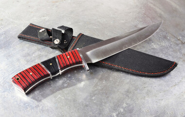 Hunting knife with sheath, with a wide single-edged sharpened blade, on an isolated background.