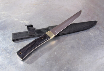 Hunting knife with a hard textile sheath, with a wide single-edged sharpened blade, on an isolated...