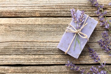 Aromatic soap bar and lavender flowers on wooden table, flat lay. Space for text