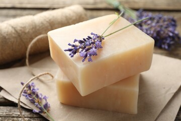 Aromatic soap bars and lavender flowers on wooden table, closeup