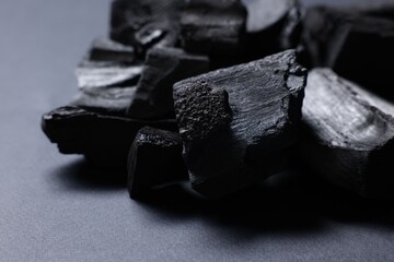 Pieces of black coals on grey table, closeup